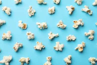 Photo of Tasty popcorn on light blue background, flat lay