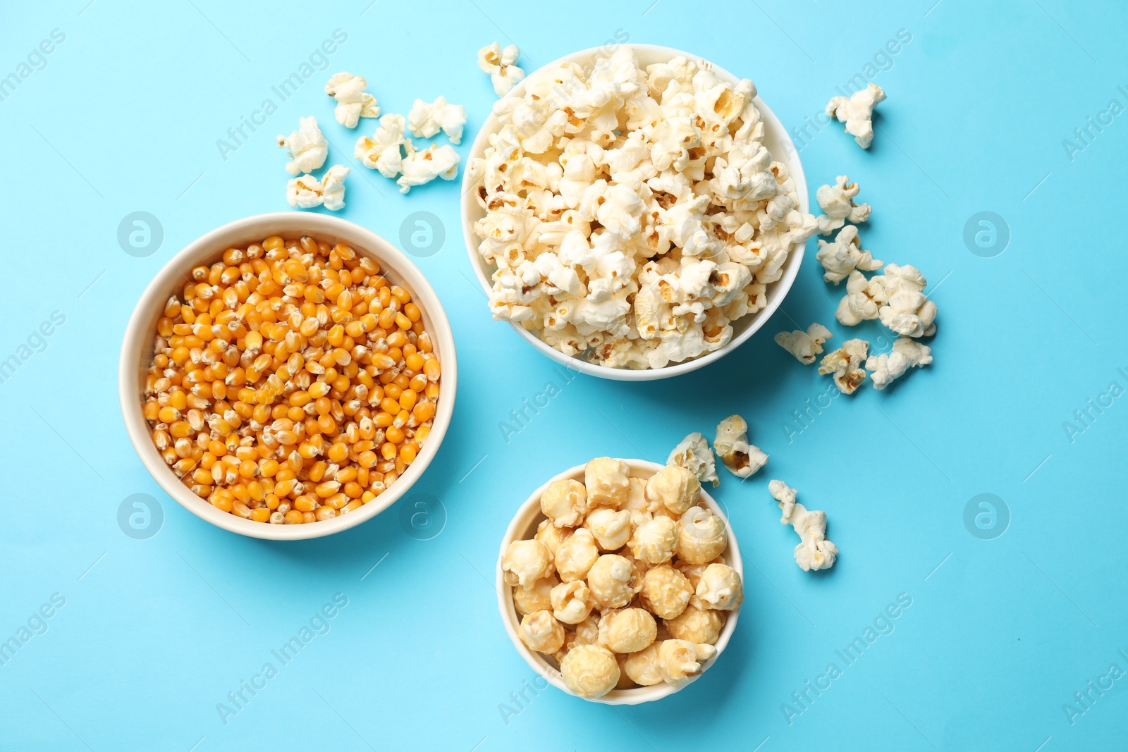 Tasty popcorn and dry kernels in bowls on light blue background, flat lay Photo of Tasty popcorn and dry kernels in bowls on light blue background, flat lay