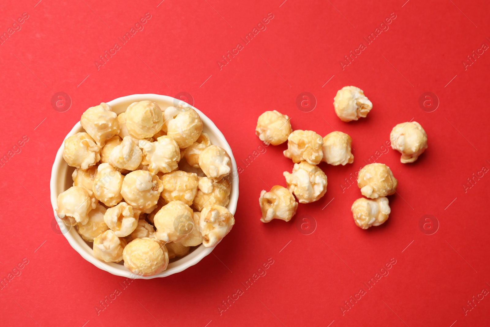 Tasty popcorn in bowl on red background, flat lay Photo of Tasty popcorn in bowl on red background, flat lay