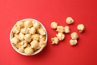 Photo of Tasty popcorn in bowl on red background, flat lay