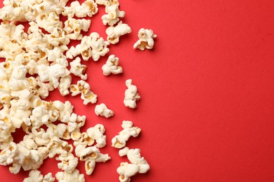 Photo of Tasty popcorn on red background, flat lay. Space for text