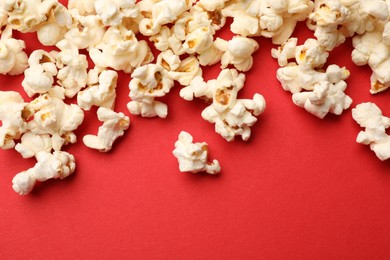 Photo of Tasty popcorn on red background, flat lay. Space for text