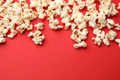 Photo of Tasty popcorn on red background, flat lay. Space for text