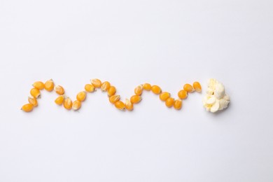 Photo of Tasty popcorn and dry kernels on white background, flat lay
