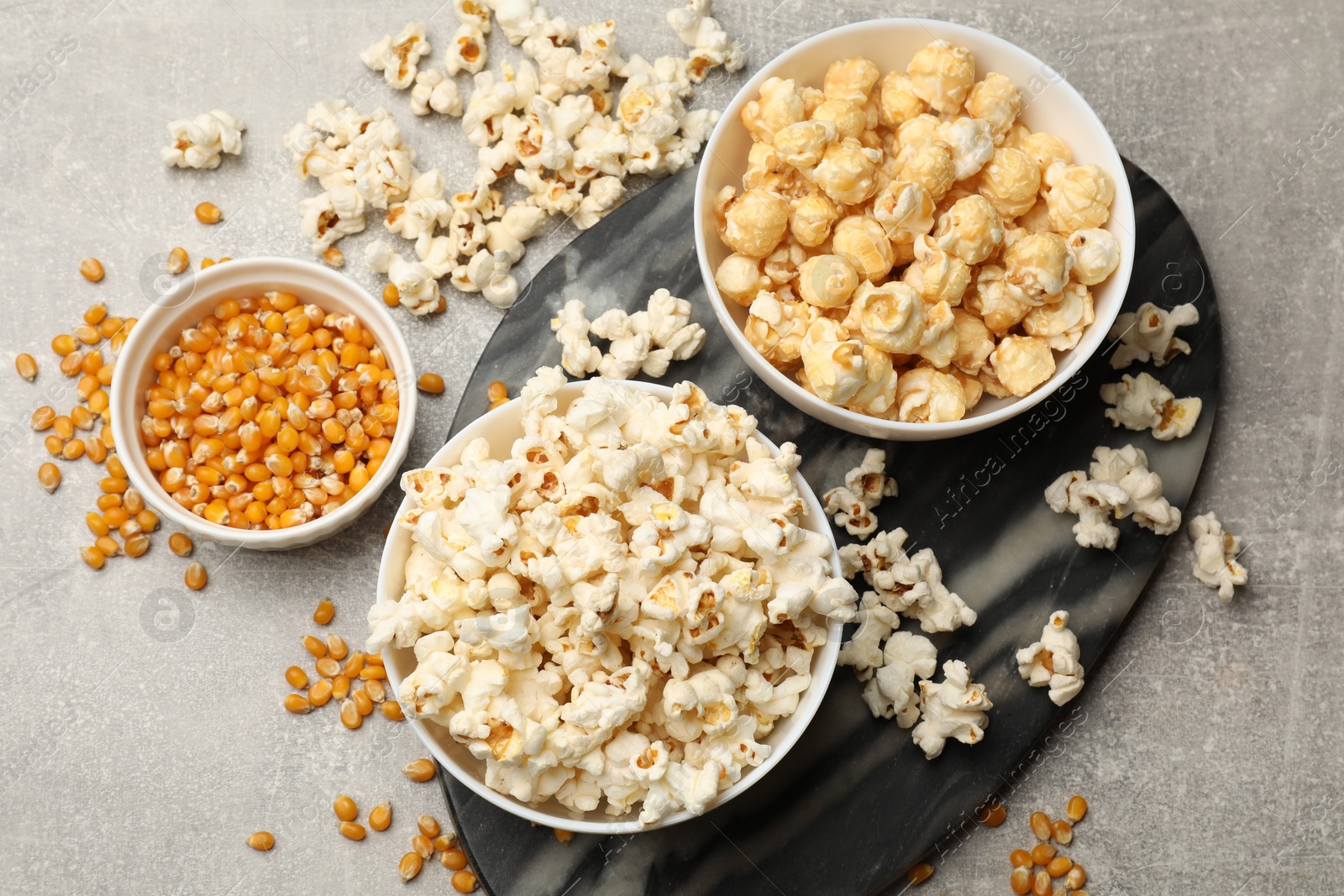 Tasty popcorn and corn kernels on light grey table, flat lay Photo of Tasty popcorn and corn kernels on light grey table, flat lay