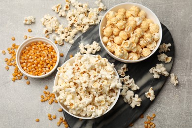 Photo of Tasty popcorn and corn kernels on light grey table, flat lay