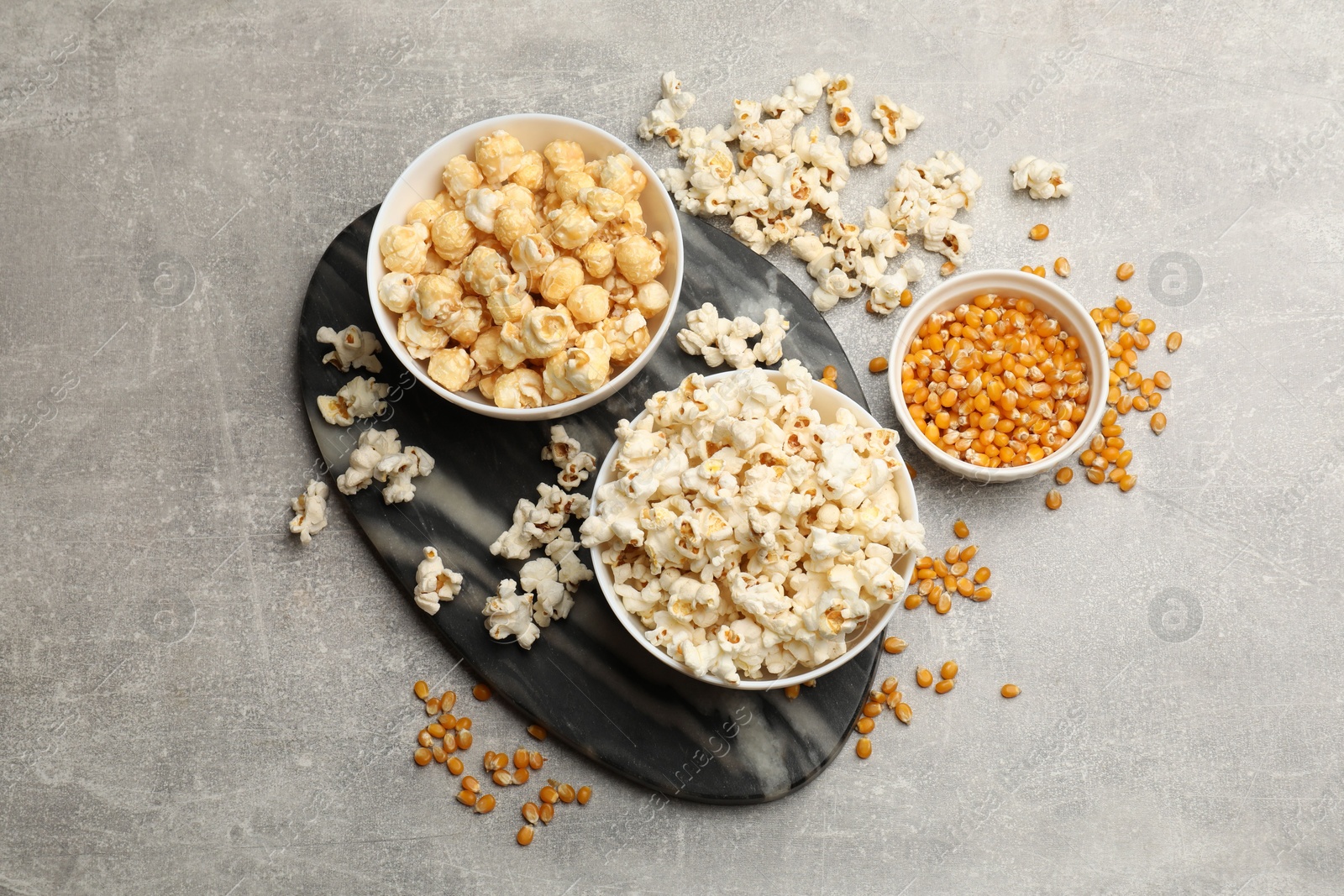 Tasty popcorn and corn kernels on light grey table, flat lay Photo of Tasty popcorn and corn kernels on light grey table, flat lay