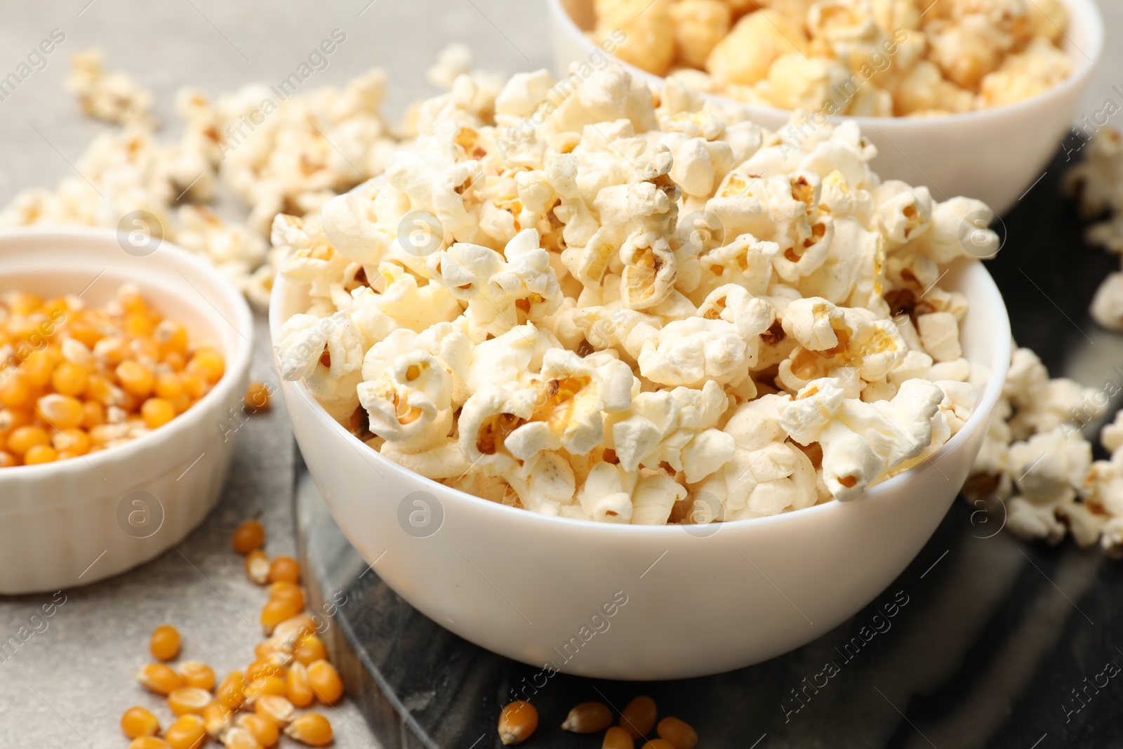Tasty popcorn and corn kernels on light grey table, closeup Photo of Tasty popcorn and corn kernels on light grey table, closeup