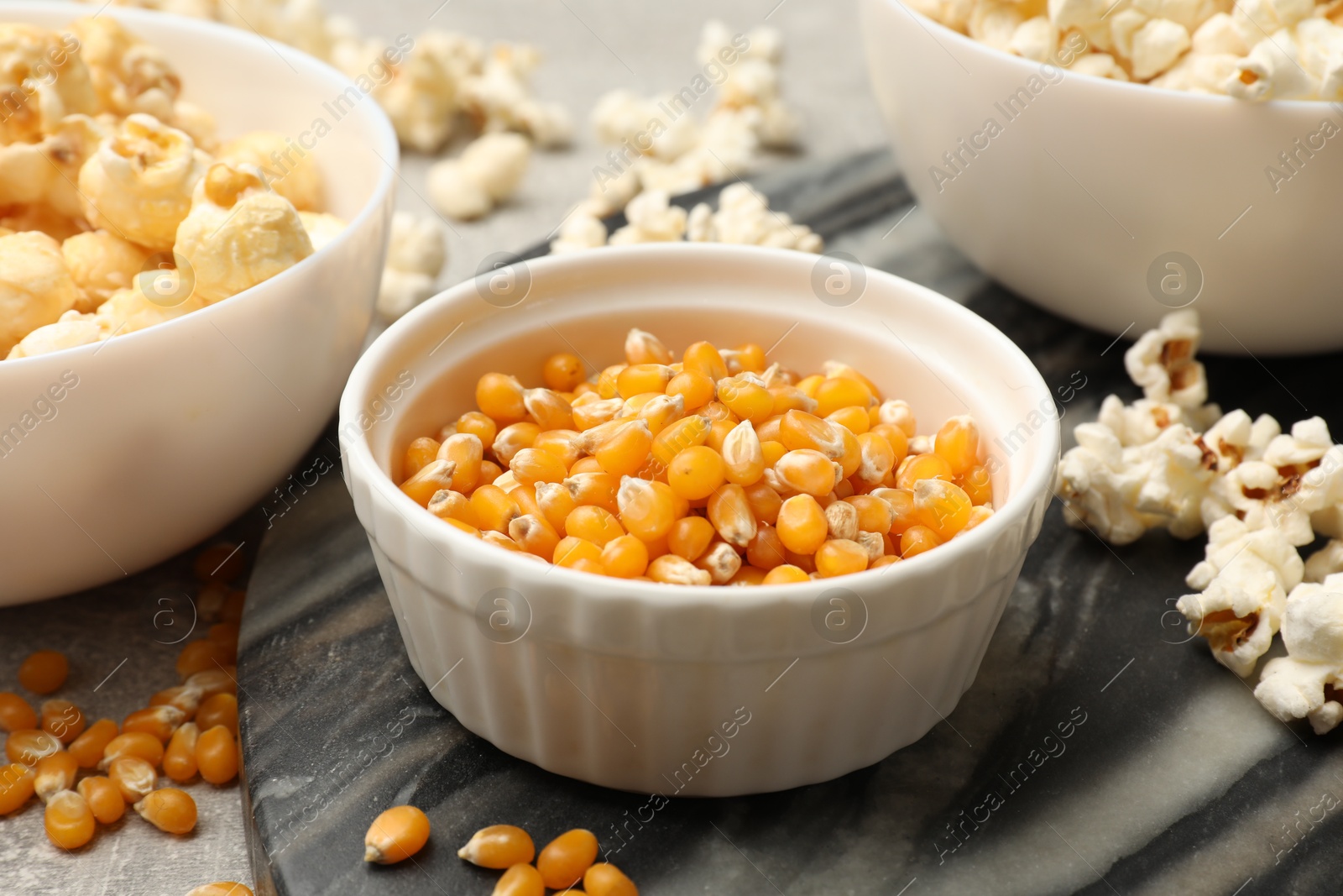 Tasty popcorn and corn kernels on light grey table, closeup Photo of Tasty popcorn and corn kernels on light grey table, closeup