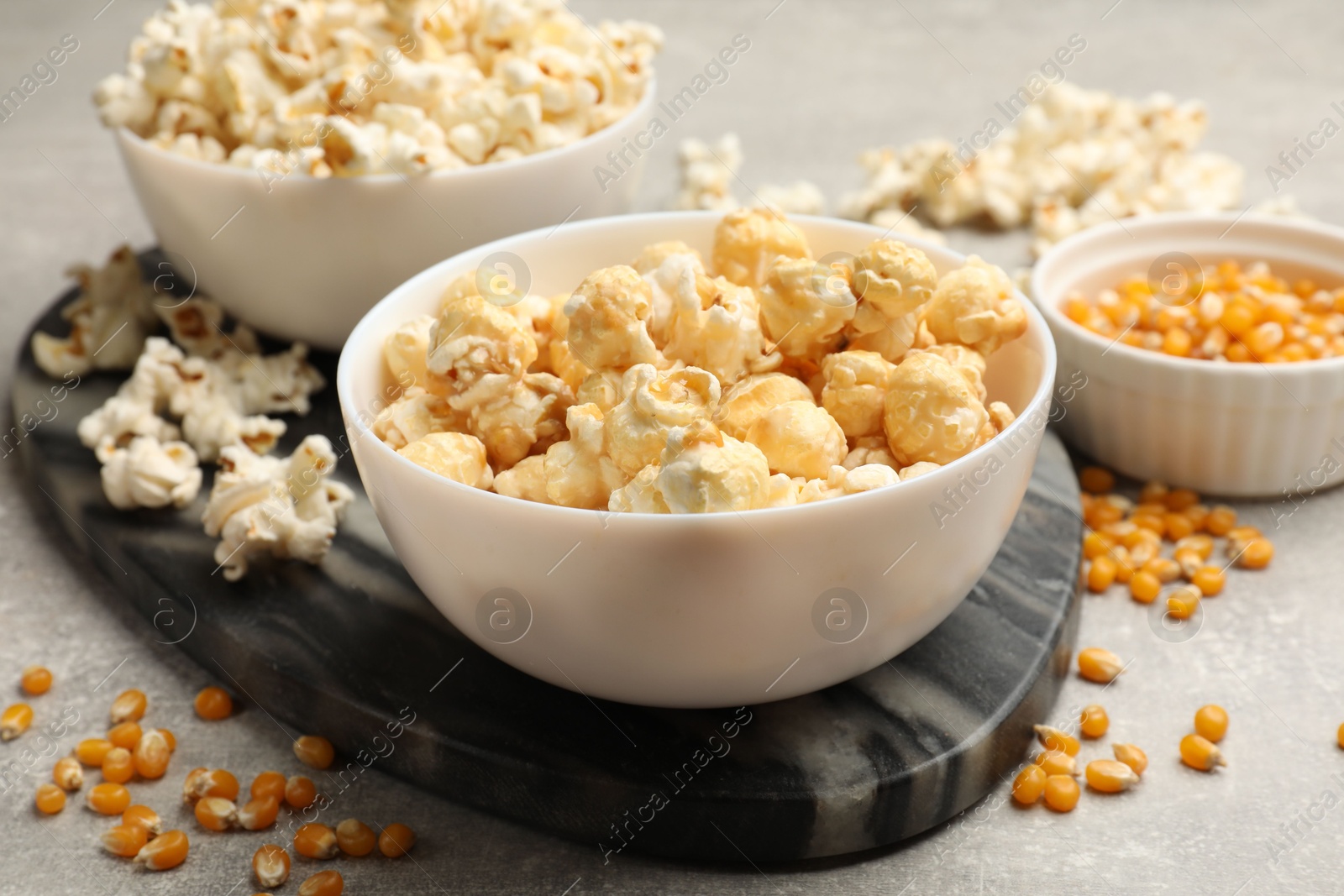 Tasty popcorn and corn kernels on light grey table, closeup Photo of Tasty popcorn and corn kernels on light grey table, closeup