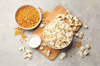 Photo of Tasty popcorn and corn kernels on light grey table, flat lay