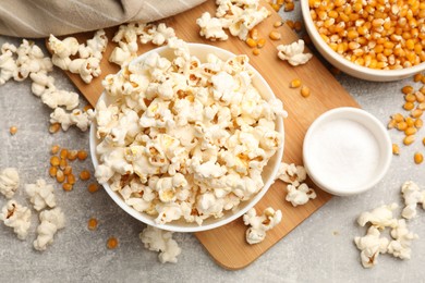 Photo of Tasty popcorn and corn kernels on light grey table, flat lay