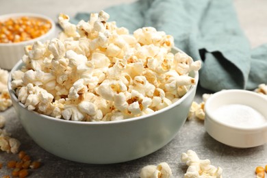 Photo of Tasty popcorn and corn kernels on light grey table, closeup