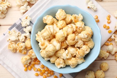 Photo of Tasty popcorn and corn kernels on light wooden table, flat lay