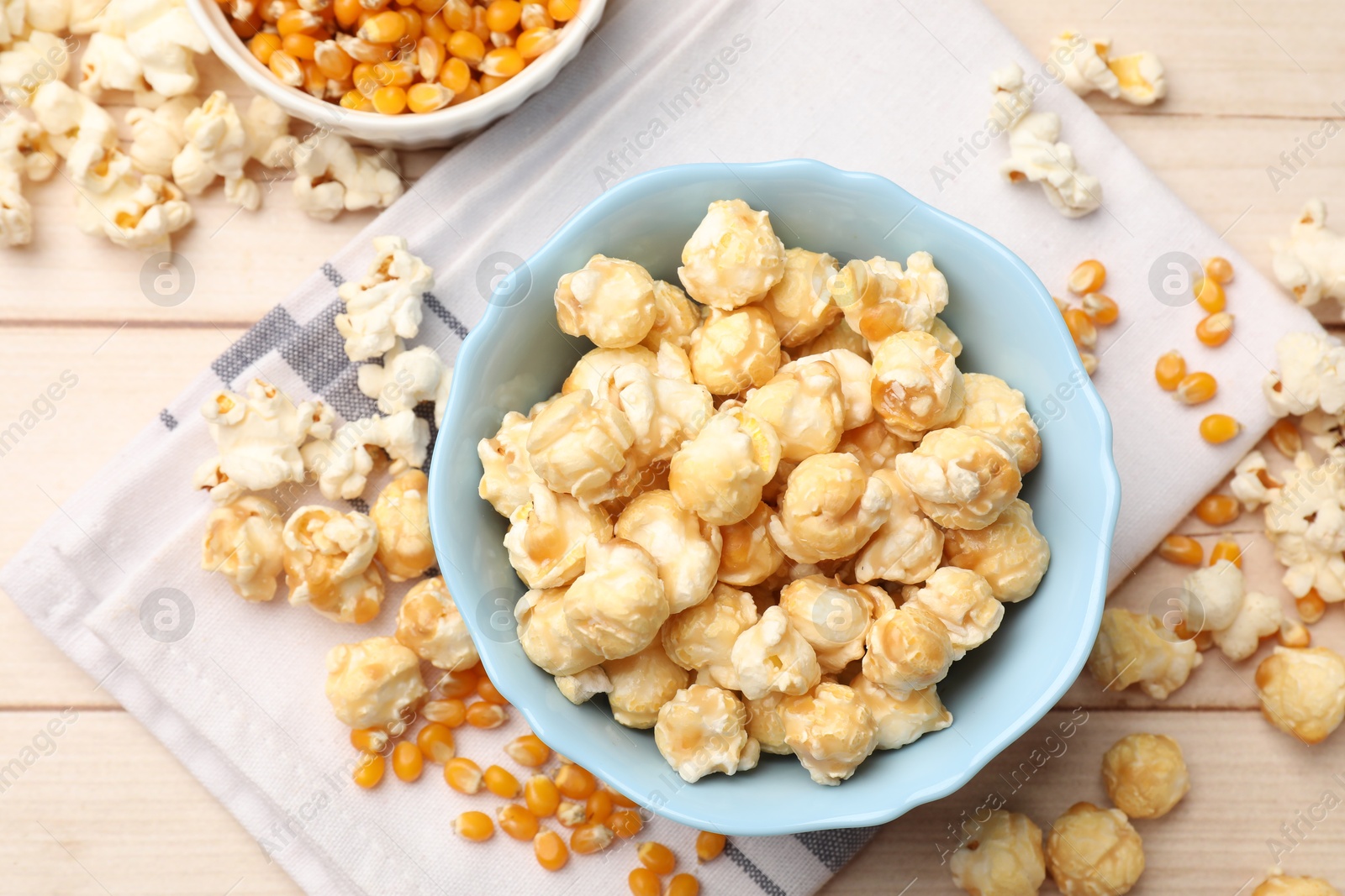 Tasty popcorn and corn kernels on light wooden table, flat lay Photo of Tasty popcorn and corn kernels on light wooden table, flat lay