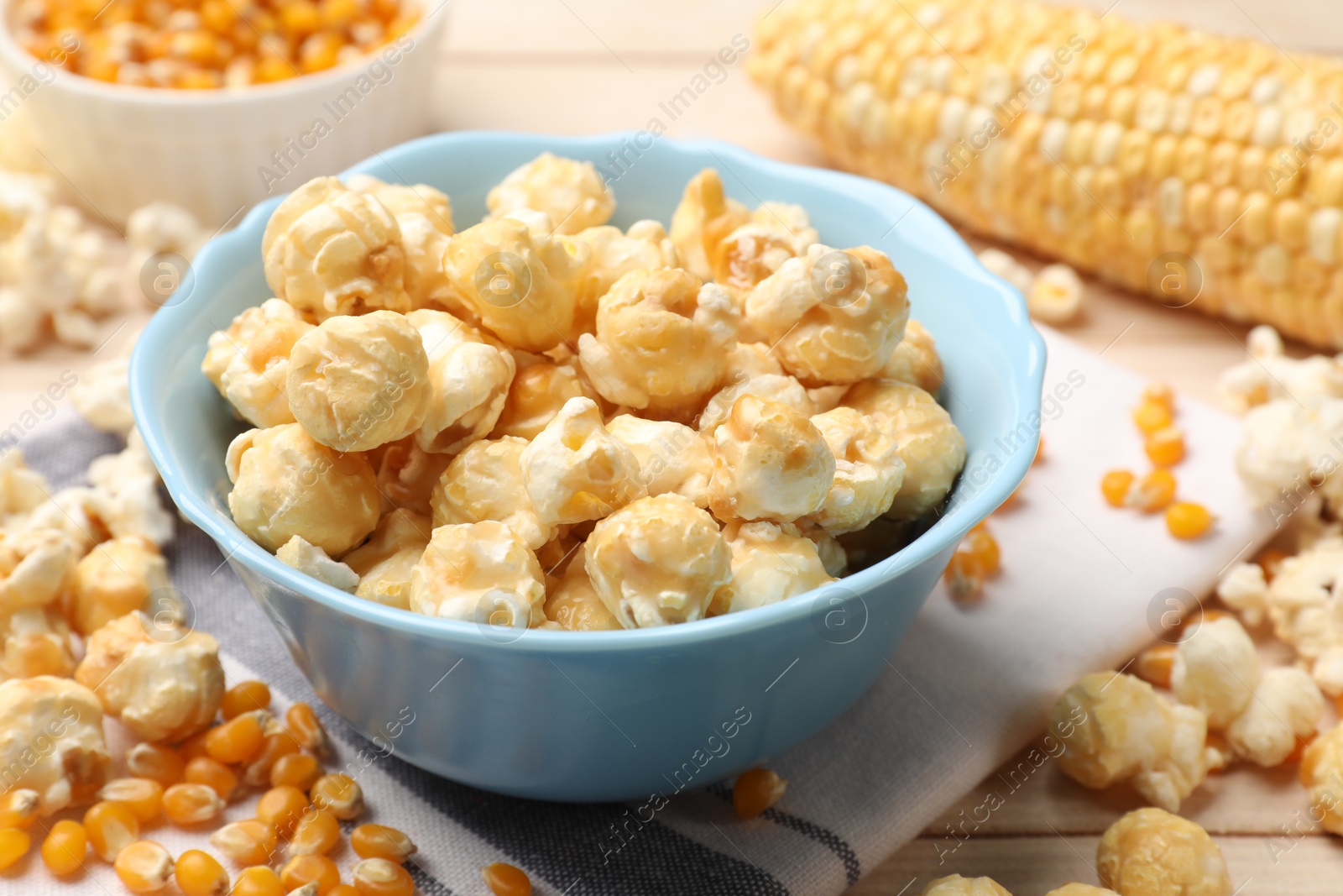 Tasty popcorn and corn kernels on light wooden table, closeup Photo of Tasty popcorn and corn kernels on light wooden table, closeup
