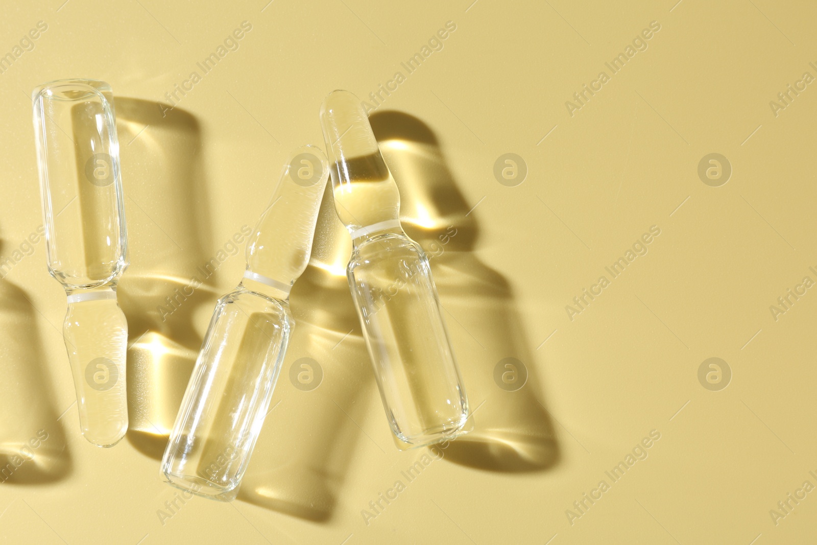 Glass ampoules with liquid on yellow background, flat lay Photo of Glass ampoules with liquid on yellow background, flat lay