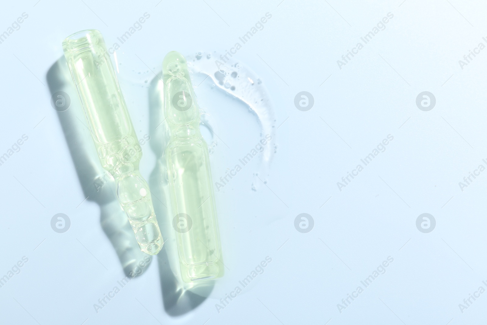 Glass ampoules with liquid on light blue background, flat lay Photo of Glass ampoules with liquid on light blue background, flat lay