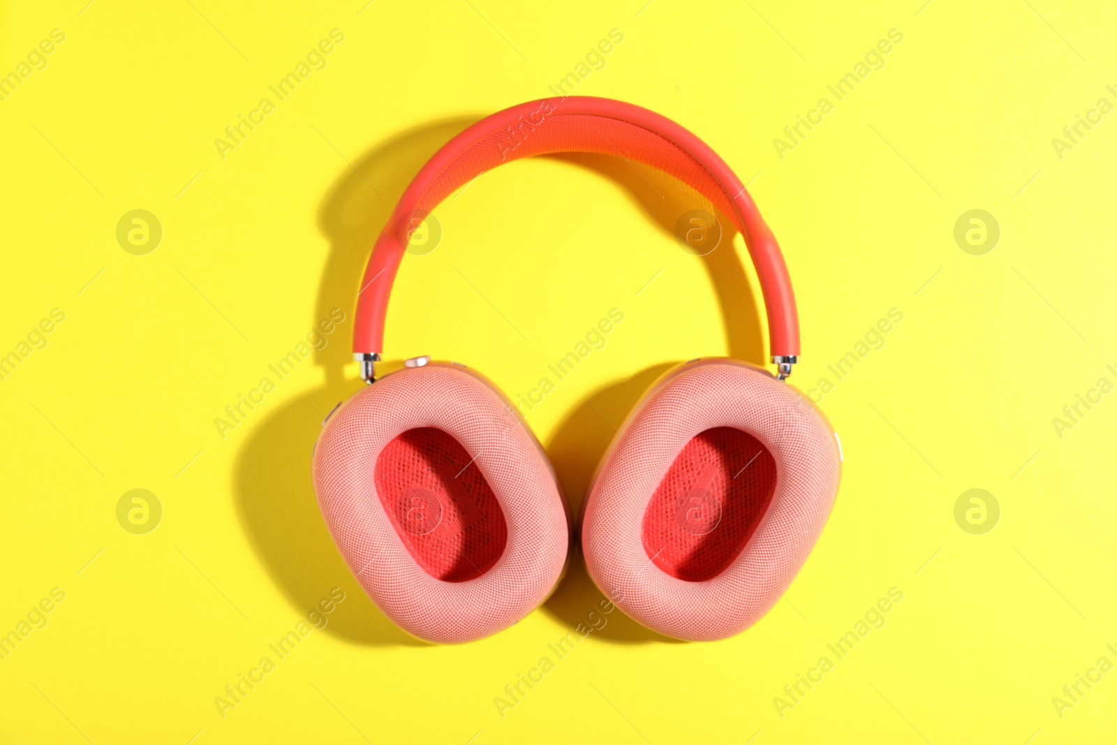 Pair of stylish pink headphones on yellow background, top view Photo of Pair of stylish pink headphones on yellow background, top view