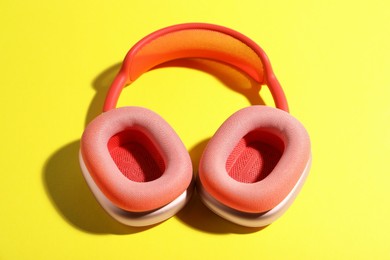 Photo of Pair of stylish pink headphones on yellow background