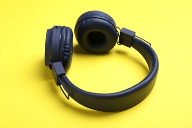 Photo of Pair of stylish blue headphones on yellow background