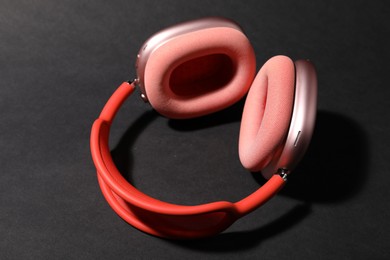 Photo of Pair of stylish pink headphones on black background