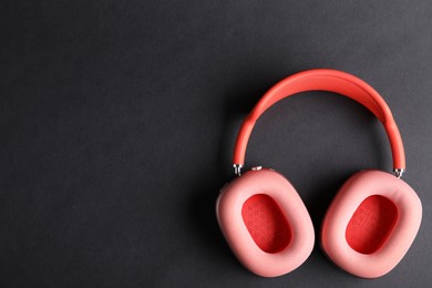 Photo of Pair of stylish pink headphones on black background, top view. Space for text