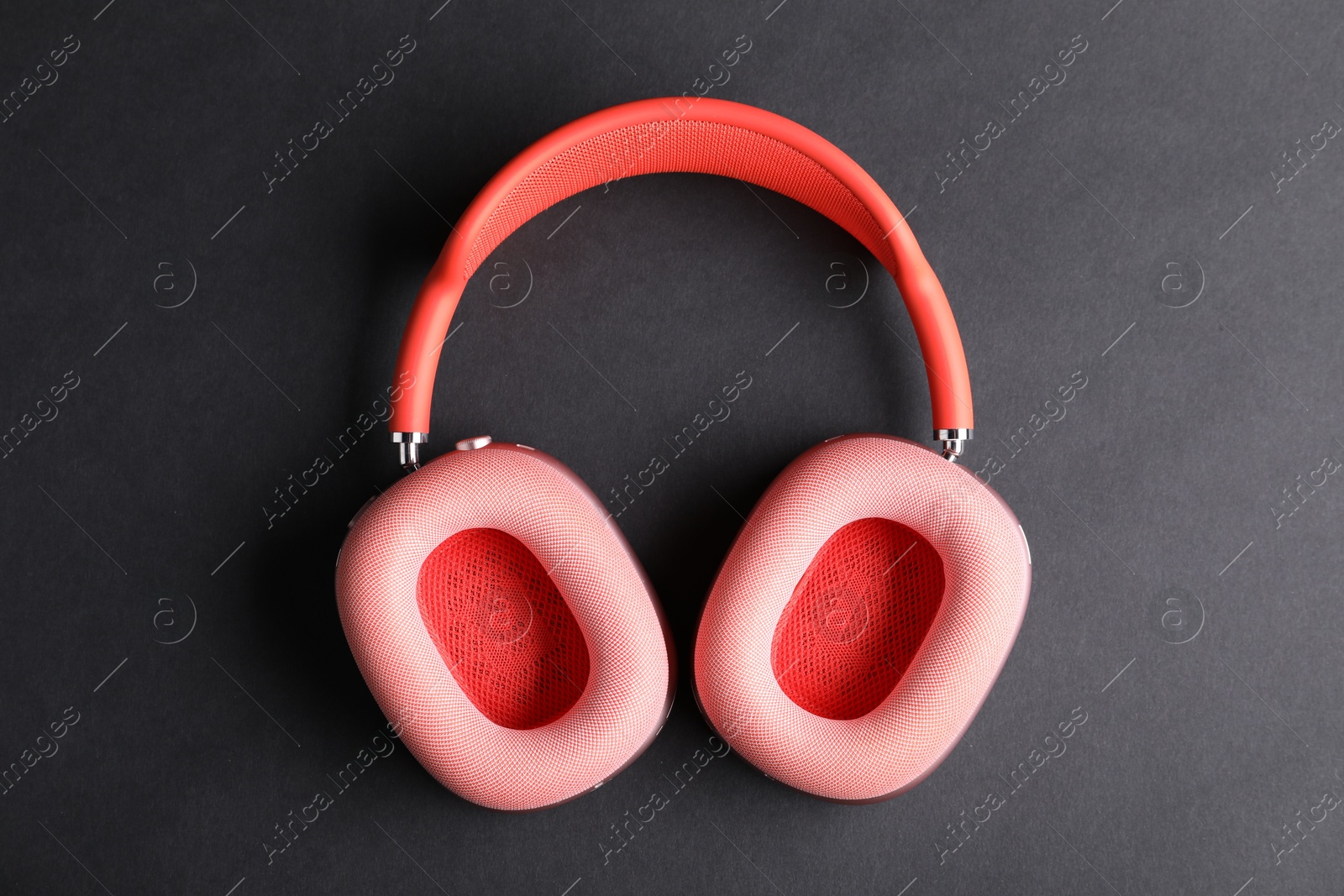 Pair of stylish pink headphones on black background, top view Photo of Pair of stylish pink headphones on black background, top view