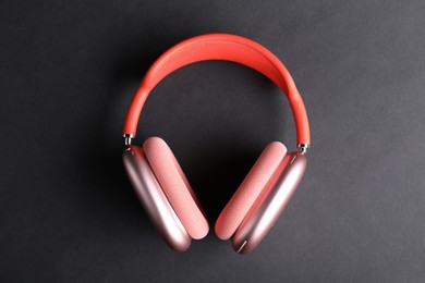 Photo of Pair of stylish pink headphones on black background, top view