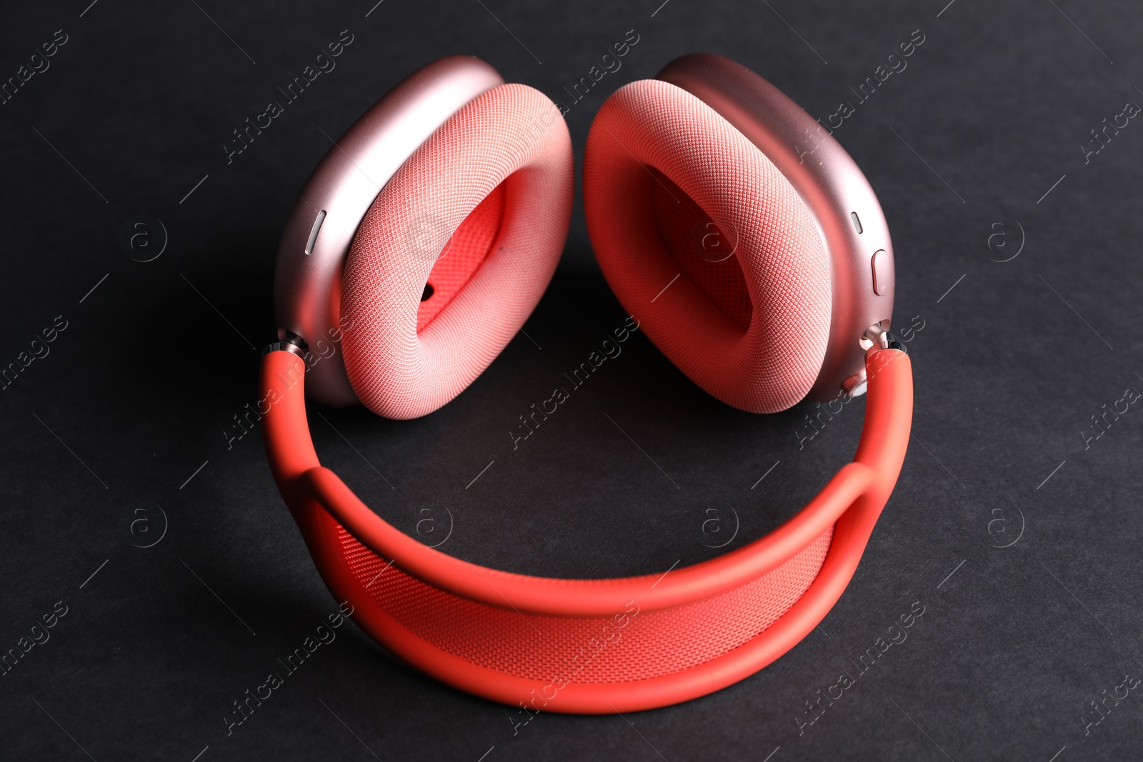 Pair of stylish pink headphones on black background, closeup Photo of Pair of stylish pink headphones on black background, closeup