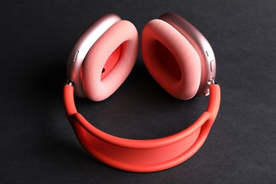 Photo of Pair of stylish pink headphones on black background, closeup