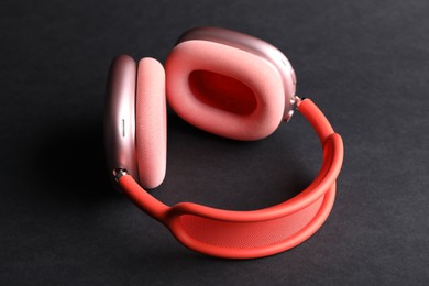 Photo of Pair of stylish pink headphones on black background, closeup