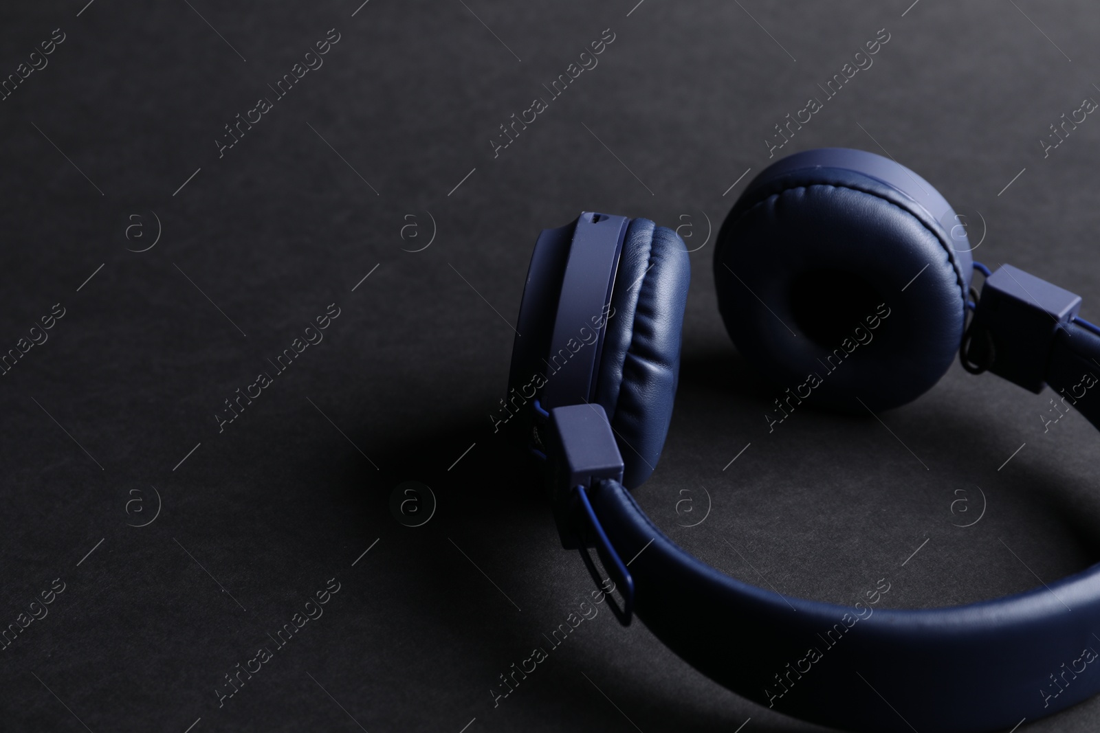 Pair of stylish blue headphones on black background, closeup. Space for text Photo of Pair of stylish blue headphones on black background, closeup. Space for text