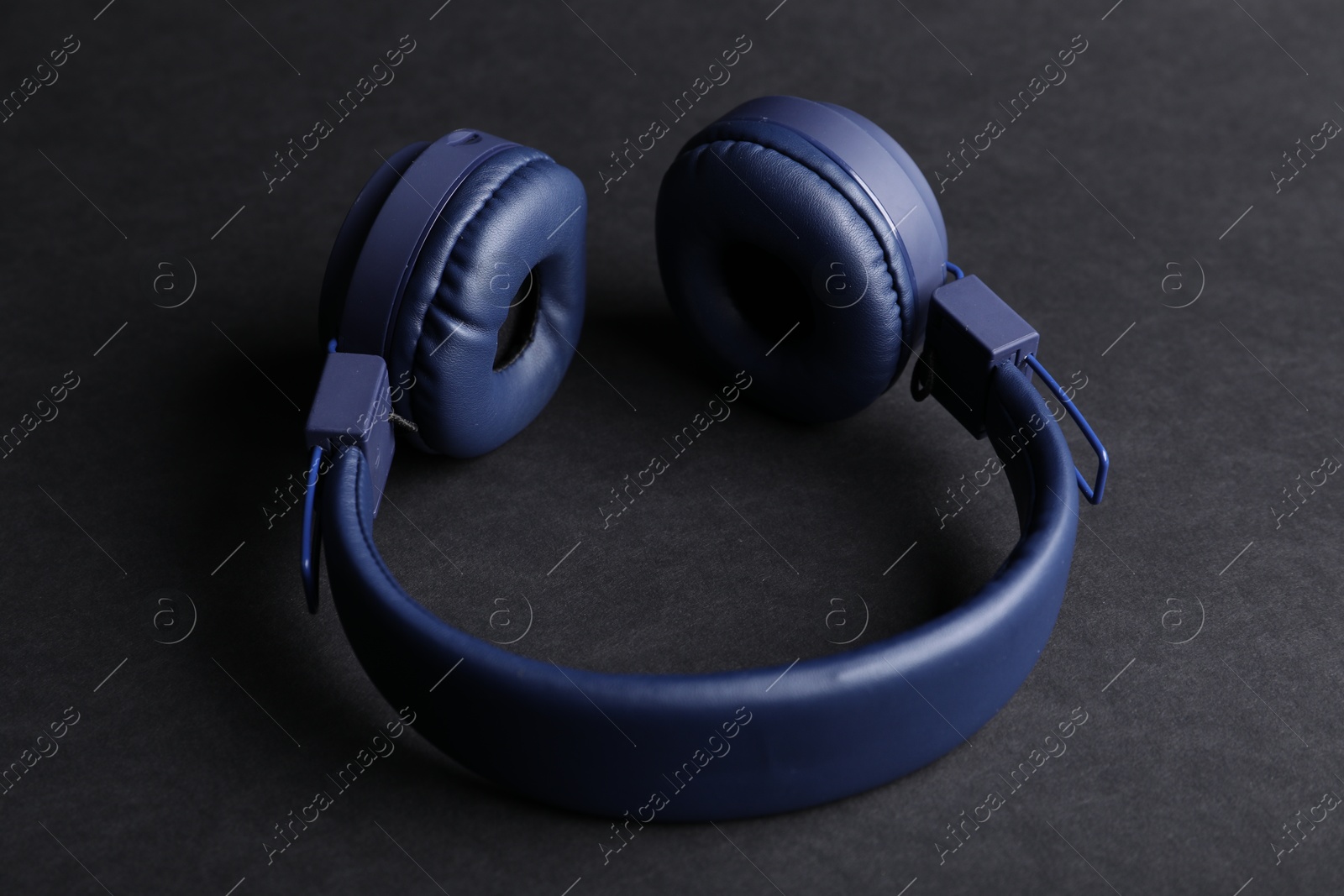 Pair of stylish blue headphones on black background Photo of Pair of stylish blue headphones on black background