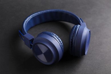 Photo of Pair of stylish blue headphones on black background, closeup