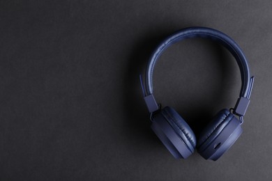 Photo of Pair of stylish blue headphones on black background, top view. Space for text
