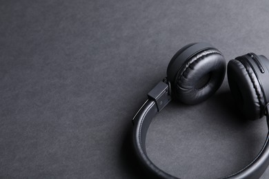 Photo of Pair of stylish headphones on black background, closeup. Space for text