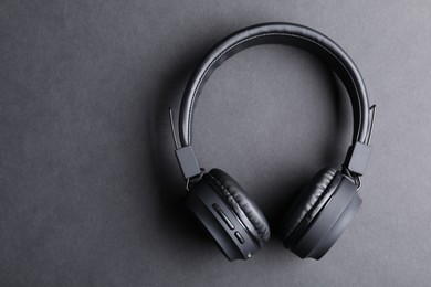 Photo of Pair of stylish headphones on black background, top view. Space for text