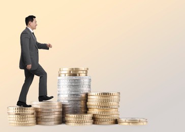 Image of Businessman walking up stacked coins against beige gradient background. Path to wealth