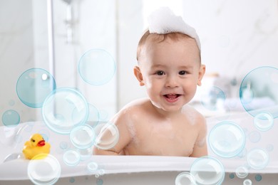 Image of Cute little baby taking bath at home. Soap bubbles in air