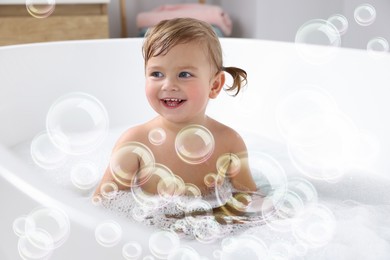 Image of Cute little girl taking bath at home. Soap bubbles in air