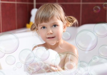 Image of Cute little girl taking bath at home. Soap bubbles in air