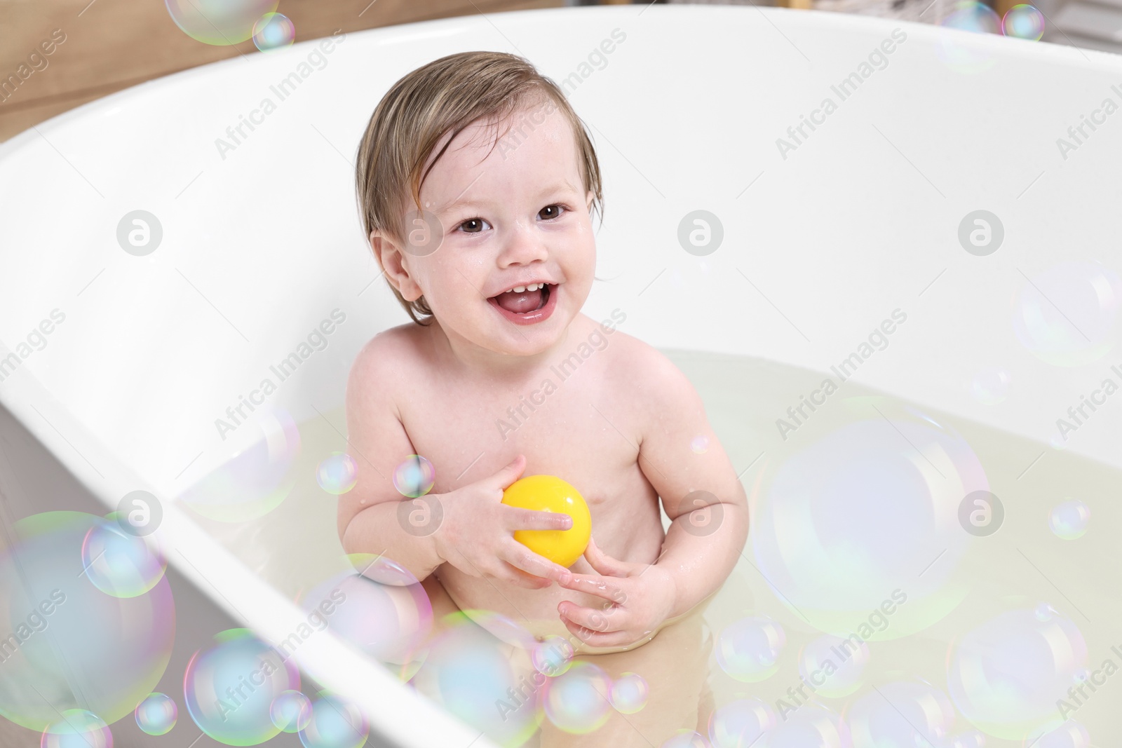 Cute little baby playing with toy while taking bath at home. Soap bubbles in air Image of Cute little baby playing with toy while taking bath at home. Soap bubbles in air