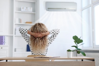 Image of Woman sitting at workplace in office with air conditioning, back view