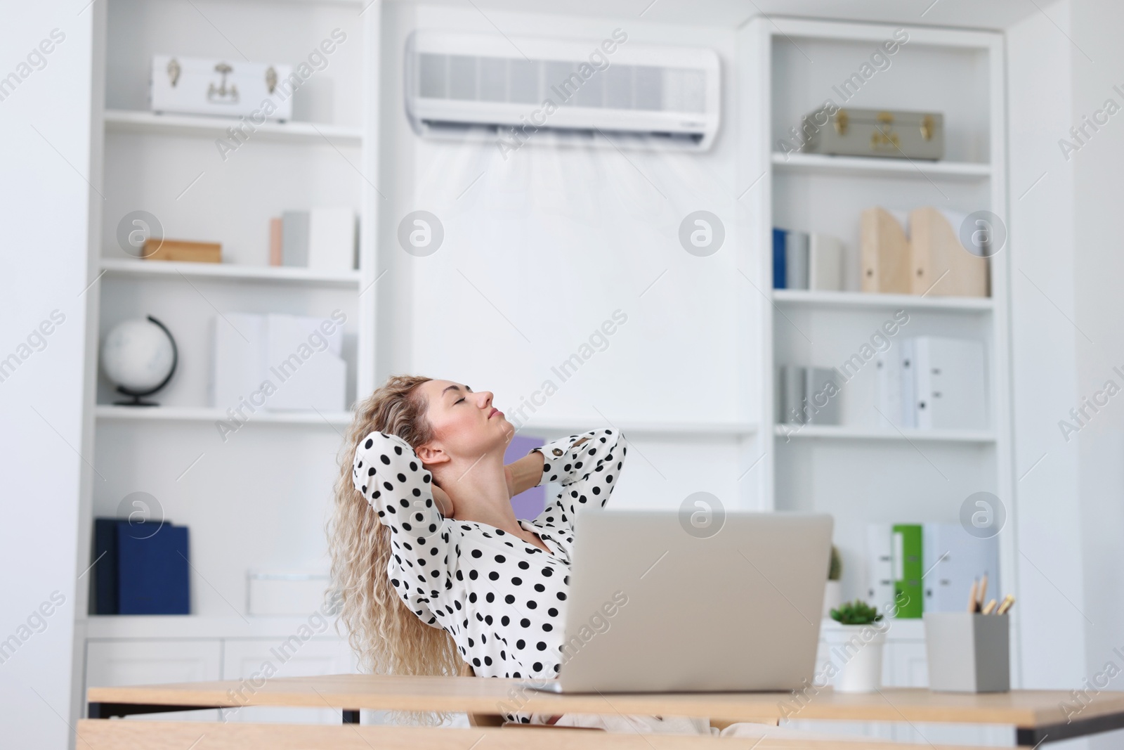 Image of Woman enjoying comfortable temperature at work with air conditioning