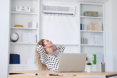 Image of Woman enjoying comfortable temperature at work with air conditioning