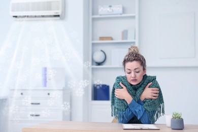 Image of Broken air conditioner or temperature set too low. Woman with scarf freezing at workplace in office