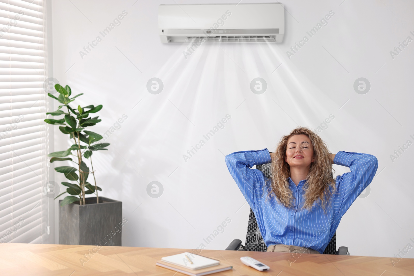 Woman enjoying comfortable temperature at work with air conditioning Image of Woman enjoying comfortable temperature at work with air conditioning