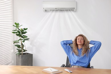 Image of Woman enjoying comfortable temperature at work with air conditioning