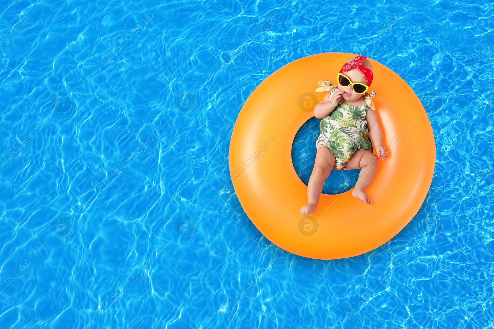 Image of Cute little baby with inflatable ring in swimming pool, top view. Space for text